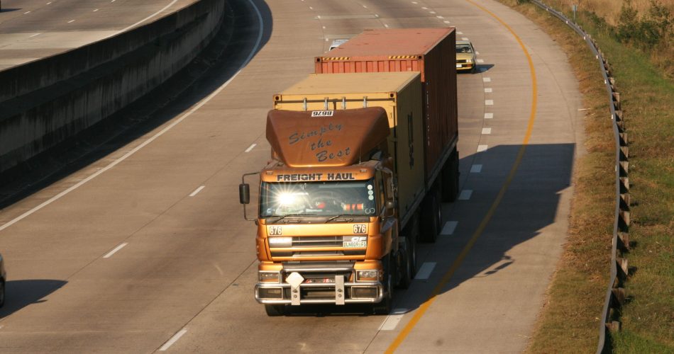 Red cargo container truck driving on a highway - land freight transport and logistics for landlocked Nepal imports